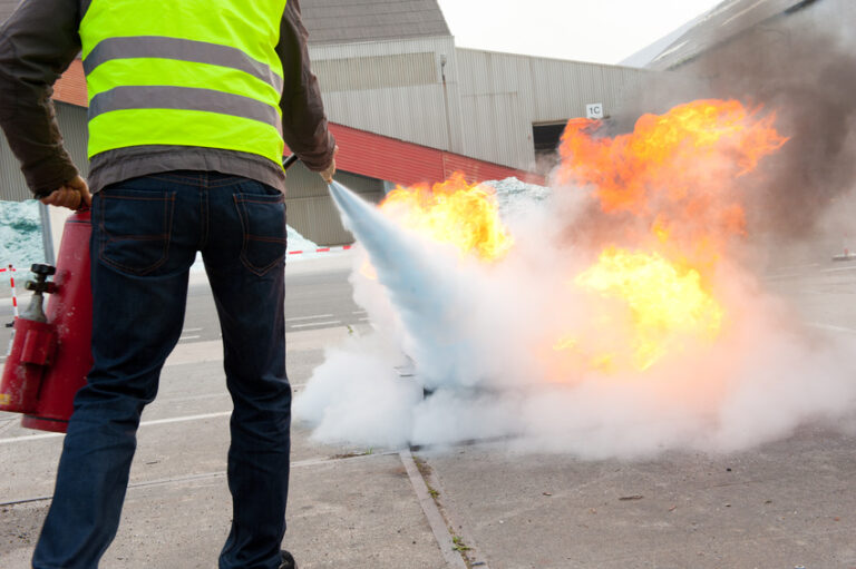 Mann löscht Feuer mit Feuerlöscher.